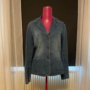 Jeansjacka med kavajkrage och fickor - Snygg jeansjacka i klassisk blå denim med kavajkrage och tre knappar framtill. Jackan har två stora fickor framtill och markerade sömmar som ger en cool, skräddad look, den påminner om en kavaj. Från vero Moda, står ingen storlek men passar en s-m.