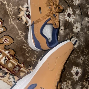 Beige finskor med blåa detaljer - Sprillans nya snygga finskor i beige med blå insida och vit på kanterna med coola märket fashion. .Materialet ser ut som syntet och de har en stilren, modern look som passar till många outfits. Aldrig använda, ordinarie pris var 300kr. Möts upp i Stockholm helst! Storlek 46.