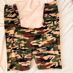 Camo leggings med hög midja - Snygga leggings med klassiskt camouflage-mönster i grönt, brunt och beige. Hög midja och stretchigt material som sitter tight och bekvämt. Perfekta för en streetstyle-look eller till träning.