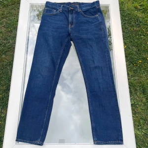 Nudie Jeans Grindy Jackson blå jeans - Säljer ett par Nudie Jeans Gritty Jackson i tvätten Nutty Worn. Storlek W31 L30. Mörkblå lätt tvättad denim, 100% bomull. Klassisk rak passform (regular fit). Jeansen är knappt använda och i mycket gott skick utan hål, fläckar eller slitage. Bara att höra av sig vid minsta fundering!