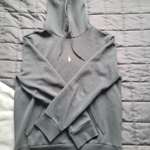 Svart hoodie från Ralph Lauren - Svart hoodie från Ralph Lauren med klassisk vit broderad logga på bröstet.. Perfekt för en chill och stilren look. Materialet är mjuk bomull.
