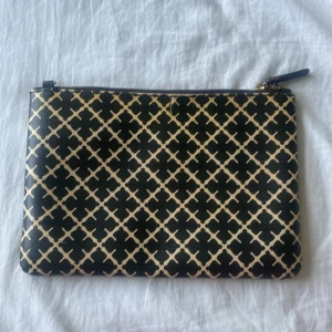  kuvertväska från By Malene Birger - Kuvertväska från By Malene Birger i svart och beige med deras ikoniska grafiska mönster. Den är super fin men den har små defekter! FÖRST TILL KVARN💕💕 