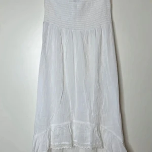 Vit somrig klänning/kjol med volang - Superfin vit klänning/kjol  i luftig bomull med smock upptill och volangdetalj nertill. Perfekt för varma dagar och har en enkel design med spetskant längst ner.