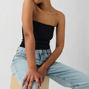 Svart bandeau tubtopp - Enkel och stilren svart bandeau tubtopp i stretchigt material. Toppen är axelbandslös och sitter tight mot kroppen, perfekt att matcha med jeans eller kjol. Snygg minimalistisk look som funkar året runt. Ny med prislapp🖤