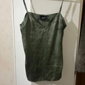 Grön topp från Only - Snygg grön topp från Only med justerbara axelband och v-ringning. Perfekt för en stilren look. 