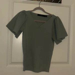 Grön ribbad topp från Vero Moda - Snygg grön ribbad topp från Vero Moda med v-ringning och korta puffärmar. Toppen har en mjuk och bekväm passform. I storlek Large passar över medium/small🤍 pris kan diskuteras!