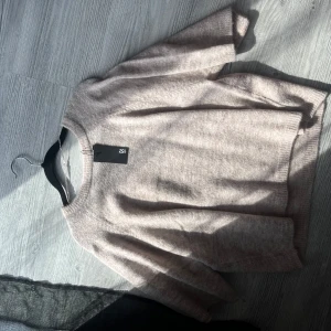 Beige stickad tröja från lager157 - Säljer en stilren beige stickad tröja från lager157 Tröjan har en normal passform med trekvartsärmar och en rund halsringning. Helt ny i storlek small
