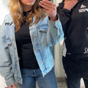 Ljusblå jeansjacka - Säljer en klassisk ljusblå jeansjacka med lite baggy passform . Jackan har knappar framtill och två bröstfickor. Perfekt för vår och sommar!