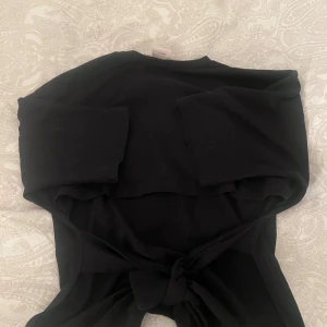 Svart tröja från Nelly - Säljer en stilren svart tröja från Nelly efter som att den var för stor för mig 💞Tröjan har trekvarts ärmar och en knytning baktill som ger en snygg detalj. Perfekt för en enkel och chic look. 🩷