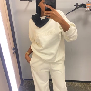 Vit tracksuit från JD - Säljer en stilren vit sweatshirt och mjukisbyxor från JD med broderad logga på framsidan. Tröjan har långa ärmar och ribbade muddar vid ärmslut och nederkant. Perfekt för en avslappnad look.