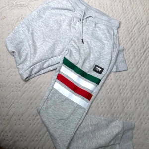 19V69 byxor - Säljer ett par grå 19V69 byxor i mjukt material med snygga ränder i grönt, vitt och rött på sidan. Ny pris≈1600kr Mitt pris= 299kr!