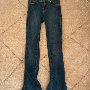 Mörkblåa jeans med låg midja från Bik Bok - Snygga mörkblåa jeans med låg flare och låg midja. De är från Bik Bok och är i storlek S. Perfekta för en avslappnad stil. De har en klassisk femficksdesign och är tillverkade i ett bekvämt denimtyg. Nypris 499kr. 