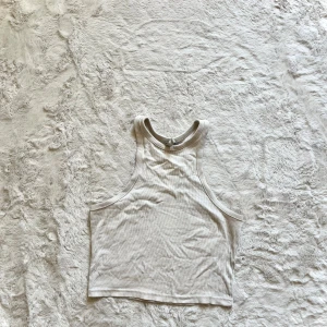 Vit ribbad linnetopp - Säljer en stilren vit ribbad linnetopp. Den är ärmlös och har en rund halsringning. Perfekt för varma dagar eller som ett lager under en jacka.