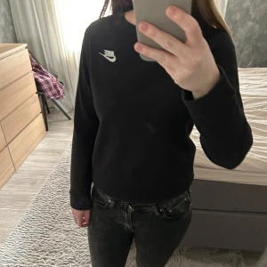 Svart långärmad tröja från Nike - Säljer en stilren svart långärmad tröja från Nike med deras ikoniska logga i vitt på bröstet. Perfekt för en avslappnad look. Passar bra till jeans eller träningsbyxor.