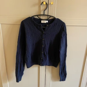 Mörkblå kofta från Kappahl - Säljer en mörkblå kofta från Kappahl med ett stickat mönster och knappar. Superbra skick trots att den används inga noppror eller liknande! 