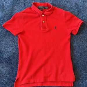 Röd pikétröja från Ralph Lauren - Säljer en klassisk röd pikétröja från Ralph Lauren i slim fit. Tröjan har korta ärmar och en broderad logga på bröstet. Perfekt för en stilren look. Hör av dig vid intresse! 🔥