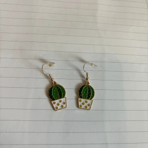 3 olika par Söta örhängen  - Tre par charmiga örhängen: ett par med gröna kaktusar i vita krukor, ett par med vita fyrklöver och ett par med turkosa bläckfiskar. Perfekta för att lägga till en lekfull touch till din stil.