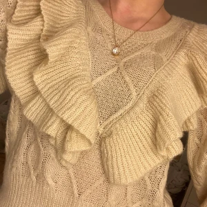 Beige stickad volangtröja💓 - Säljer denna superfina stickade tröjan med vackra volangdetaljer över bröstet och axlarna. Den har tyvärr inte kommit till användning och är iprincip i nyskick!💘