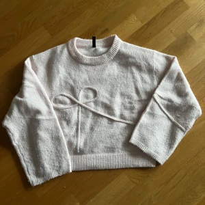 Ljusrosa stickad tröja med en rosett - Använd en gång och har inga defekter. Pris kan diskuteras skriva om ni har frågor eller vill ha fler bilder.