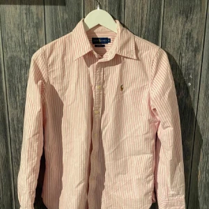 Ralph Lauren Skjorta - Rosa och vit Ralph Lauren skjorta, i princip nyskick. Öppen för prisförslag 😁Storleken är M men sitter mer som S skulle jag säga. Var inte rädd att ställa några frågor!