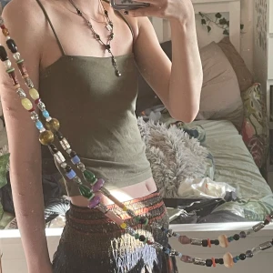 Olivgrön linnetopp - Säljer en basic olivgrön linne  med smala axelband och cropped passform. Perfekt för varma dagar och lätt att matcha med olika outfits. Toppen är enkel och bekväm, vilket gör den till ett mångsidigt tillskott i garderoben. Kan stylas till många olika klädstilar!