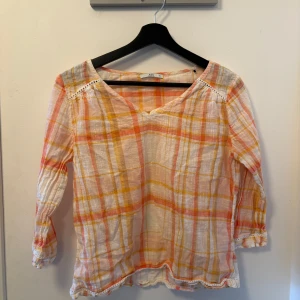 Summer blouse - Säljer en luftig och färgglad blus med rutigt mönster i rosa, orange och gult. Blusen har trekvartsärmar och en v-ringad hals. Perfekt för vår och sommar!