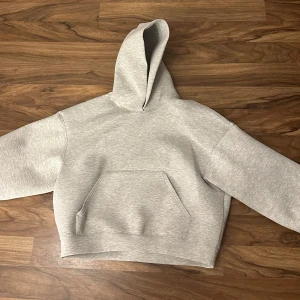 Grå hoodie - Säljer en stilren grå hoodie med en klassisk känguruficka framtill. Den har en bekväm passform och en praktisk huva. Perfekt för en avslappnad look. Den är helt ny med prislappen på och aldrig använd! Köpte den för 570kr