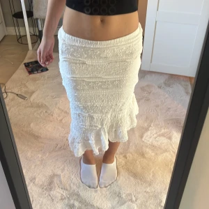 Vit kjol från Nelly - Säljer en vit kjol från Nelly med volangdetaljer. Kjolen har en smickrande passform och är perfekt för varma dagar. Den är elastisk i midjan för extra komfort. Perfekt för att skapa en stilren look. Använd en gång😚