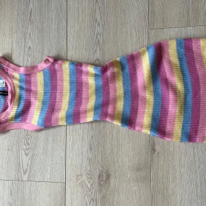 Randig ribbad klänning från Divided - Säljer en färgglad randig klänning från Divided i rosa, gul och blå. Klänningen är ribbad och ärmlös, perfekt för en somrig look. Den har en tight passform som framhäver figuren. Passar utmärkt för en dag på stan eller en avslappnad fest.🩷