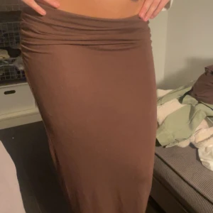 Brun långkjol - Snygg brun långkjol med tight passform. Kjolen har en rynkad detalj vid midjan som ger en fin effekt. Perfekt för att skapa en stilren look. Helt slutsåld hon Nelly köpt i januari aldrig använd 