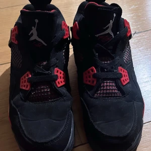 Air Jordan  -  Nike Air Jordans i svart och rött mönster  med klassisk snörning. Trampdelen i skon har lossnat och lite skrynklig där fram på skon.  Men utöver det så ser allt bra ut 