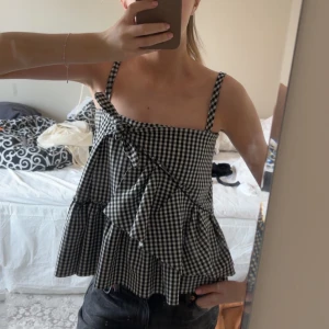 Rutig topp -  svart-vit rutig linnetopp med volangdetaljer. Toppen är omsydd därav priset.