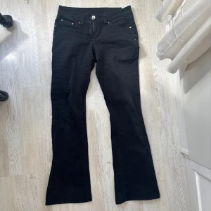 Svarta Lågmidjade bootcut jeans - Snygga svarta bootcut jeans med dragkedja och knapp framtill. Klassisk femficksdesign och lågmidjad passform. Perfekta för vårens stil! Midjemått ca 39, innerbenslängd ca 74❣️ kan ej visa dessa på då de är för korta på mig! Aldrig använda. 