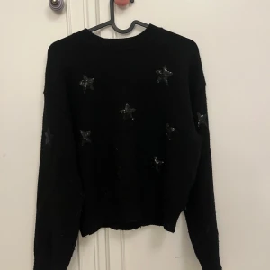 Svart stickad tröja med stjärnor - Snygg svart stickad tröja med glittriga stjärnor. Perfekt för en stilren look med en touch av glitter. Tröjan har långa ärmar och en bekväm passform. Storlek 146-152 men passar xs💗