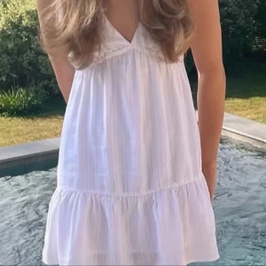 Vit klänning från Pull&Bear - Säljer en söt vit klänning från Pull&Bear i storlek S. Klänningen har en v-ringad design och är ärmlös med en luftig passform. Perfekt för varma sommardagar! 🌞