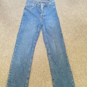 Blå jeansbyxor - Snygga blå jeansbyxor med hög midja och en klassisk femficksdesign. Byxorna har en rak passform och stängs med dragkedja och knapp. Perfekta för en avslappnad stil.