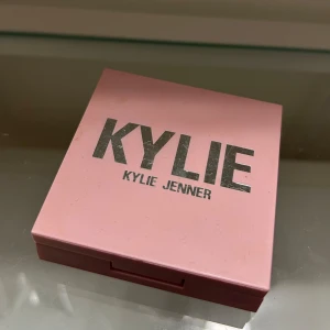 Pressed Blush Powder från Kylie Jenner - Säljer en Pressed Blush Powder i nyansen 'Baddie on the Block' från Kylie Jenner. Den kommer i en snygg rosa förpackning med spegel inuti. Perfekt för att ge kinderna en fräsch och naturlig färg.