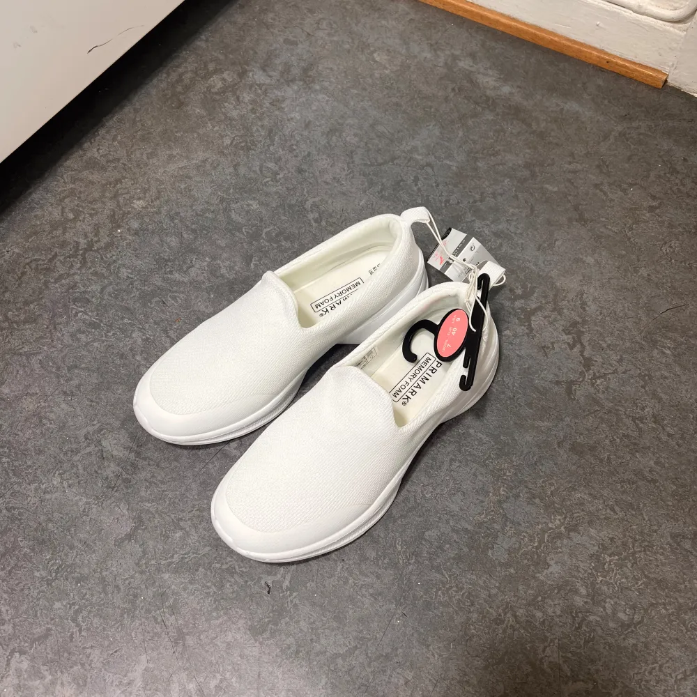 Säljer ett par vita slip-on sneakers från Primark med memory foam för extra komfort. Skorna har en enkel och stilren design utan snörning, vilket gör dem lätta att ta på och av. Perfekta för en avslappnad stil.. Kengät.