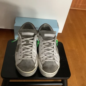 Ett par vita grå phillipe model  - Ett par phillipe model skor storklek 42. Det tvättas innan det skickas nypris på dema är 3700 isch mitt pris 1799. Skorna är prutbara kom privat för mer information eller mer bilder. Og ingår box papper och tag.