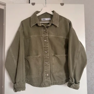 Grön jeansjacka från Zara - Säljer en snygg grön jeansjacka från Zara. Jackan har en klassisk krage och knappar framtill. Den har två stora fickor och långa ärmar med knappar vid ärmsluten. Perfekt för en avslappnad stil. Nypris 700kr (förra ägarens bilder)