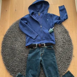 Blå jeans  - Snygga blå jeans med klassisk femficksdesign och ett stilrent bälte. Perfekta för en avslappnad look. Passar bra till både sneakers och kängor.