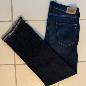 Mörkblå Replay jeans  - Snygga mörkblå jeans från Replay med klassisk femficksdesign. Jeansen har en normal passform och är tillverkade i slitstarkt denimtyg. Perfekta för dig som gillar en stilren look med diskreta detaljer och bekväm känsla.