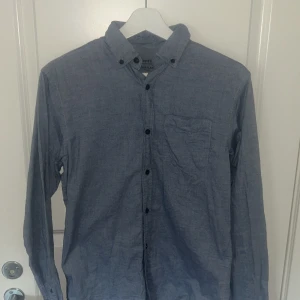 Blå flanellskjorta Essentials XS (Jack and Jones) - Snygg blå flanellskjorta från Essentials i storlek XS. Skjortan har klassisk krage med knappar, bröstficka och långa ärmar. Tillverkad i mjuk bomullsflanell, perfekt för lager-på-lager. Enkel och stilren design med svarta knappar. Knappt använd! Orginal pris 449kr
