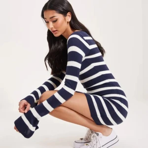 Randig stickad kortklänning, Nelly - Superfin stickad kortklänning med breda marinblå och vita ränder. Klänningen har lång ärm med lätt utsvängda ärmslut och en kroppsnära passform. Från NellyByNelly, nypris 499kr