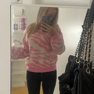 Rosa och vit zebramönstrad stickad tröja - Superfin stickad tröja med rosa och vitt zebramönster. Tröjan har rund hals, långa ärmar och ribbade muddar vid ärmslut och nederkant. 🌸🌟