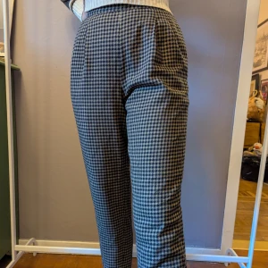 Rutiga högmidjade kostymbyxor - Snygga svartvita kostymbyxor med klassiskt rutigt mönster. Byxorna är högmidjade och har en rak passform som ger en clean och stilren look.