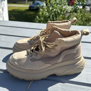 Beige chunky boots med mesh och mocka - Säljer ett par beige boots med chunky sula, snygga detaljer i mocka och mesh. Skorna har snörning och rund tå, samt dragflik bak för enkel påtagning. Perfekta för dig som gillar streetstyle och vill sticka ut med en modern look.