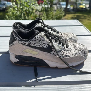 Nike Air Max 90 med svartvitt mönster - Nike Air Max 90 sneakers med svart och vitt prickigt mönster, svarta detaljer och snörning. Ovandel i mocka och syntet, svart swoosh och svartvit sula med synlig Air Max-enhet. Perfekt för dig som vill sticka ut med coola detaljer.