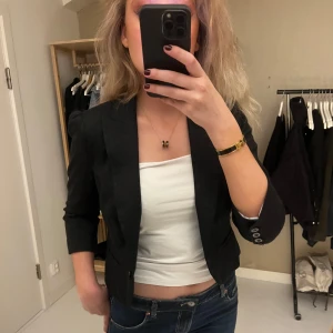Svart kavaj med trekvartsärm - Snygg svart kavaj med trekvartsärm och smal passform. Klassisk design med knappar vid ärmslut och lätt figursydd siluett. Perfekt att slänga över en topp för en clean och stilren look❤️