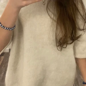 Vit stickad tröja med kort ärm - Supermjuk och enkel vit stickad tröja med korta ärmar. Kan användas till allt. Tröjan har en rak passform och är i ett mysigt material som känns skönt mot huden. (Lägger in fler bilder sen)  vi kan diskutera om priset också🫶